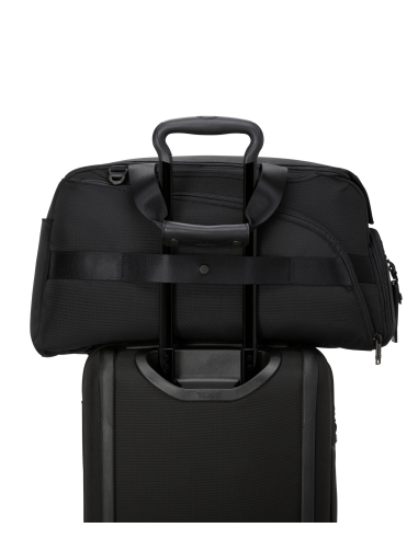 Sac de golf convertible TUMI Alpha Black, passant installé sur une poignée de valise