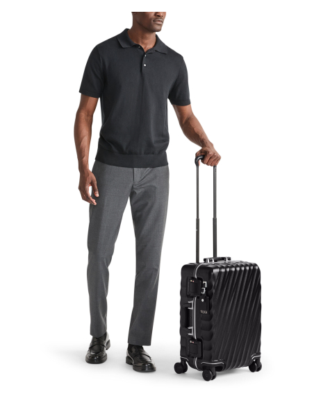 Valise cabine 55 cm TUMI 19 Degree Frame Black Texture, vue avec un voyageur, poignée déployée