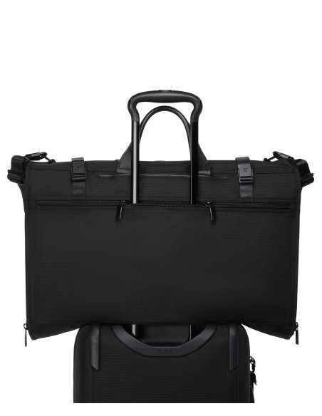 Housse porte-vêtements pliable TUMI Alpha Black, passant installé sur une poignée de valise
