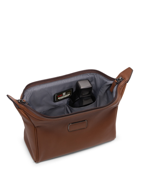 Trousse de toilette Framed TUMI en cuir lisse Cognac, ouverture encadrée avec produits illustrant le rangement
