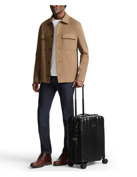 Valise cabine large extensible TUMI Latitude 55 cm Carbon Black, valise noire présentée à côté d’un voyageur