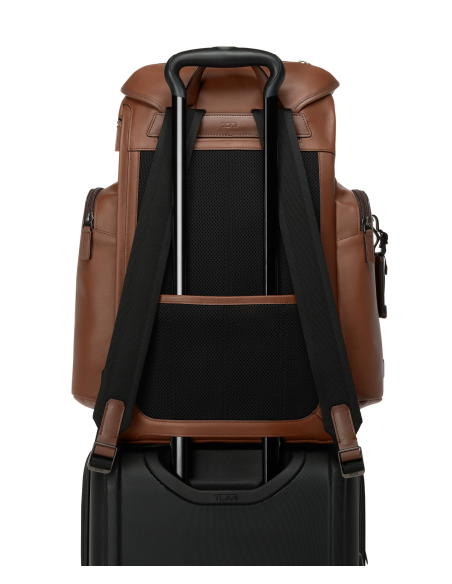 Dos du sac TUMI Harrison Griffen cuir Cognac fixé sur la poignée télescopique d’une valise