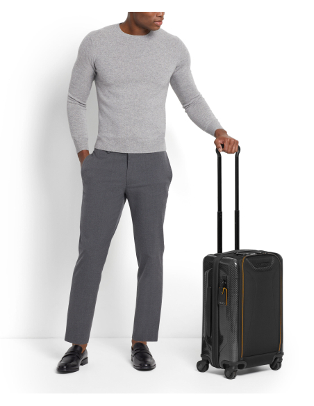 Valise cabine Aero 56 cm à panneaux moulés TUMI McLaren Black, valise debout à côté d’un voyageur