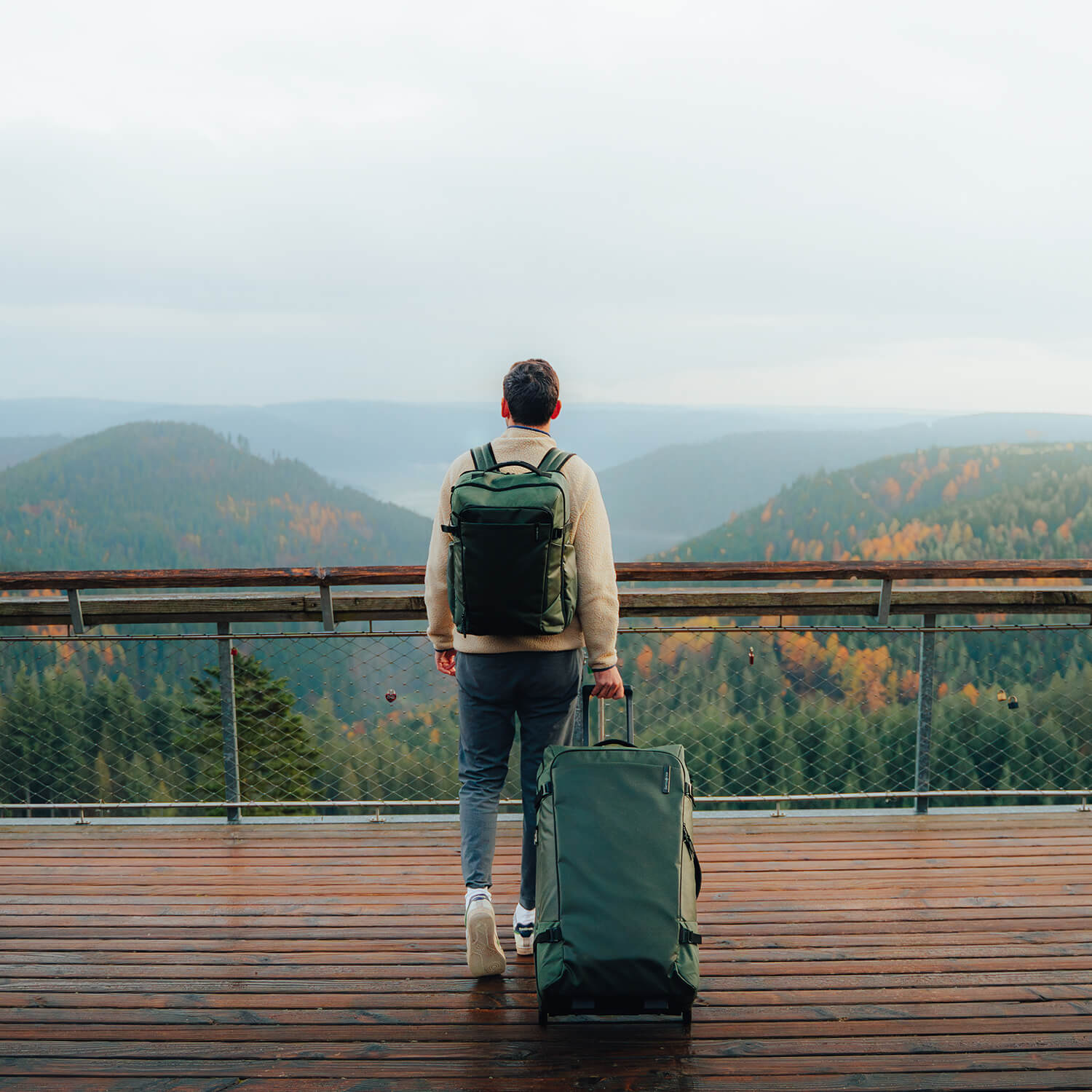 Voyageur avec un sac &agrave; dos et un sac &agrave; roulettes Samsonite Armox Moss sur une passerelle