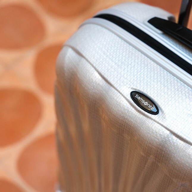 D&eacute;tail de la coque en Curv et de la poign&eacute;e d&rsquo;une valise Samsonite C-Lite claire