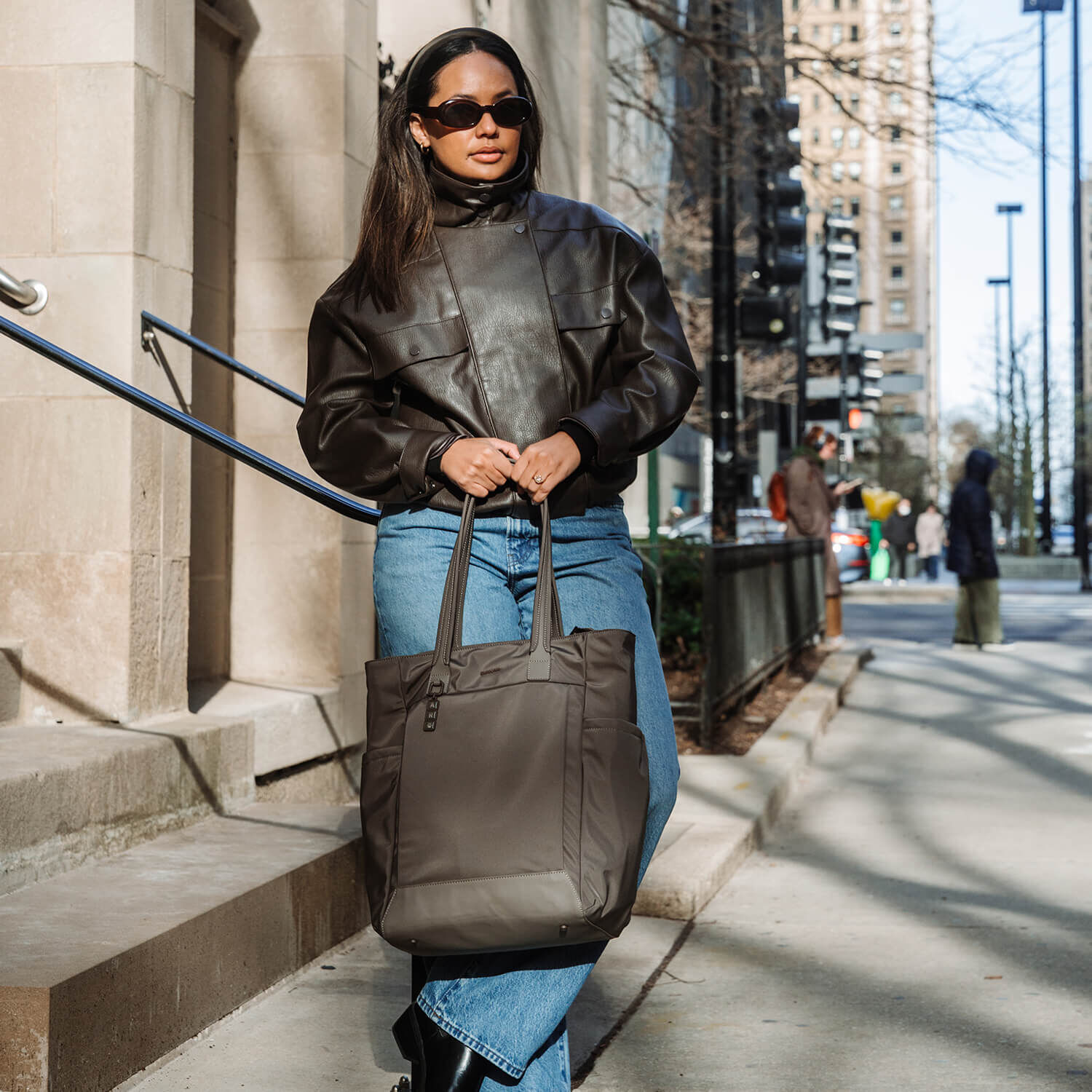 Cabas Samsonite Essentis Dark Taupe port&eacute; &agrave; la main dans une rue