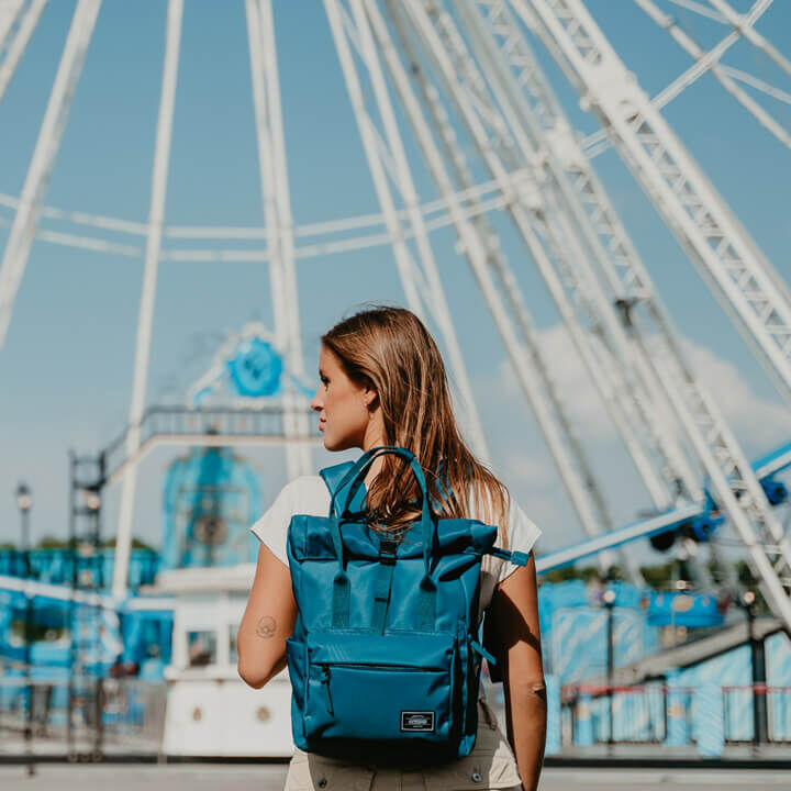 Sac &agrave; dos American Tourister Urban Groove bleu port&eacute; en ville devant une grande roue