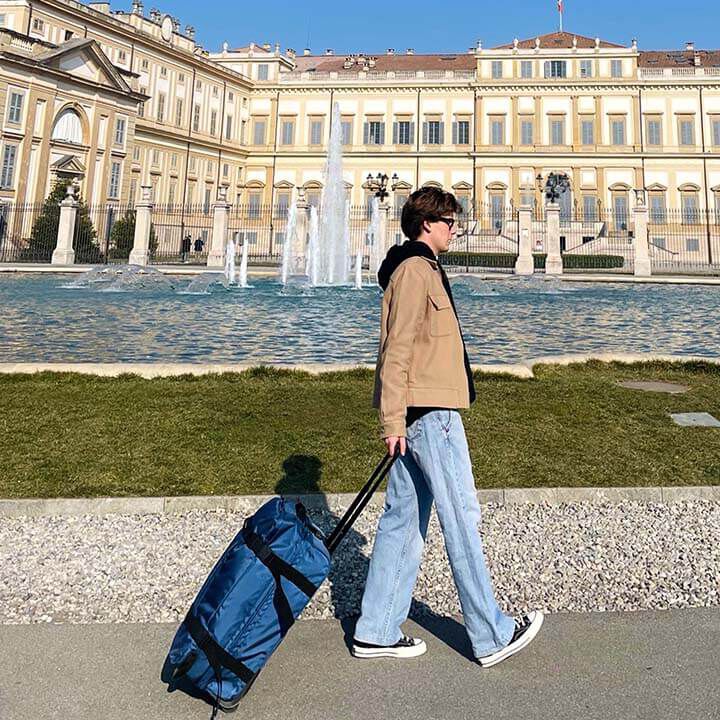 Voyageuse tirant un sac de voyage American Tourister Urban Track bleu.