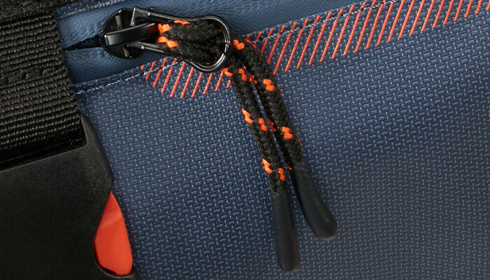 D&eacute;tail du tissu enduit et de la fermeture du sac Urban Track Coated bleu et orange.