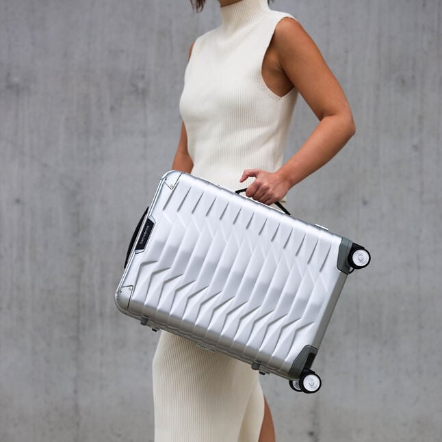 Voyageuse portant une Samsonite Proxis Alu par sa poign&eacute;e lat&eacute;rale