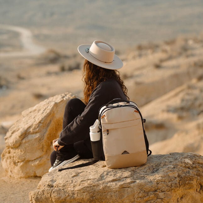 Voyageuse assise sur des rochers avec un sac à dos Samsonite Roadseeker